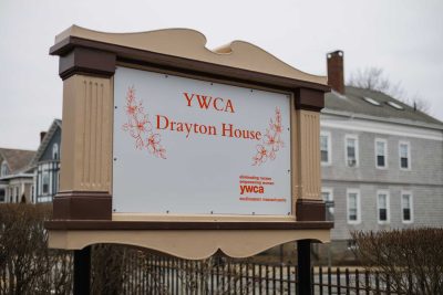 YWCA drayton house sign outside. Sign reads "YWCA Drayton House" in orange with outline of flowers on either side