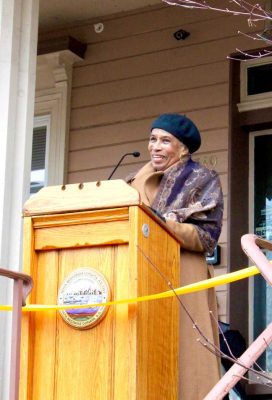 Yvonne Drayton speaking and smiling at podium at ribbon cutting for Drayton House