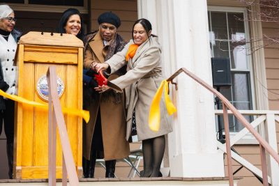 Drayton House ribbon being cut by Yvonne Drayton, Gail Fortes, and Lindsay Carter-Monteiro, the ribbon has just been cut