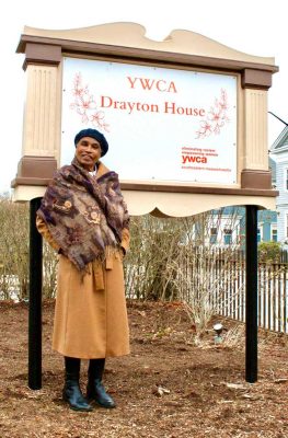 Yvonne Drayton standing next to drayton house sign outdoors