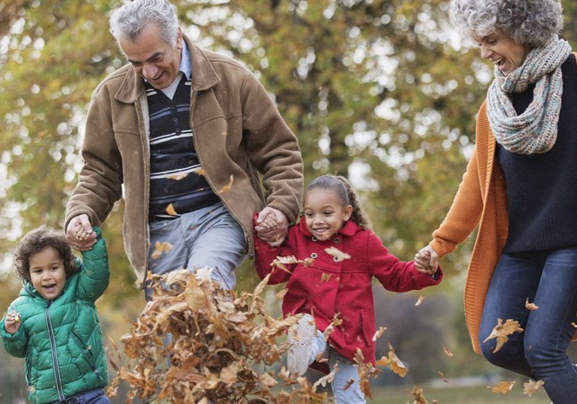 Grandparents and grandchildren kicking leaves